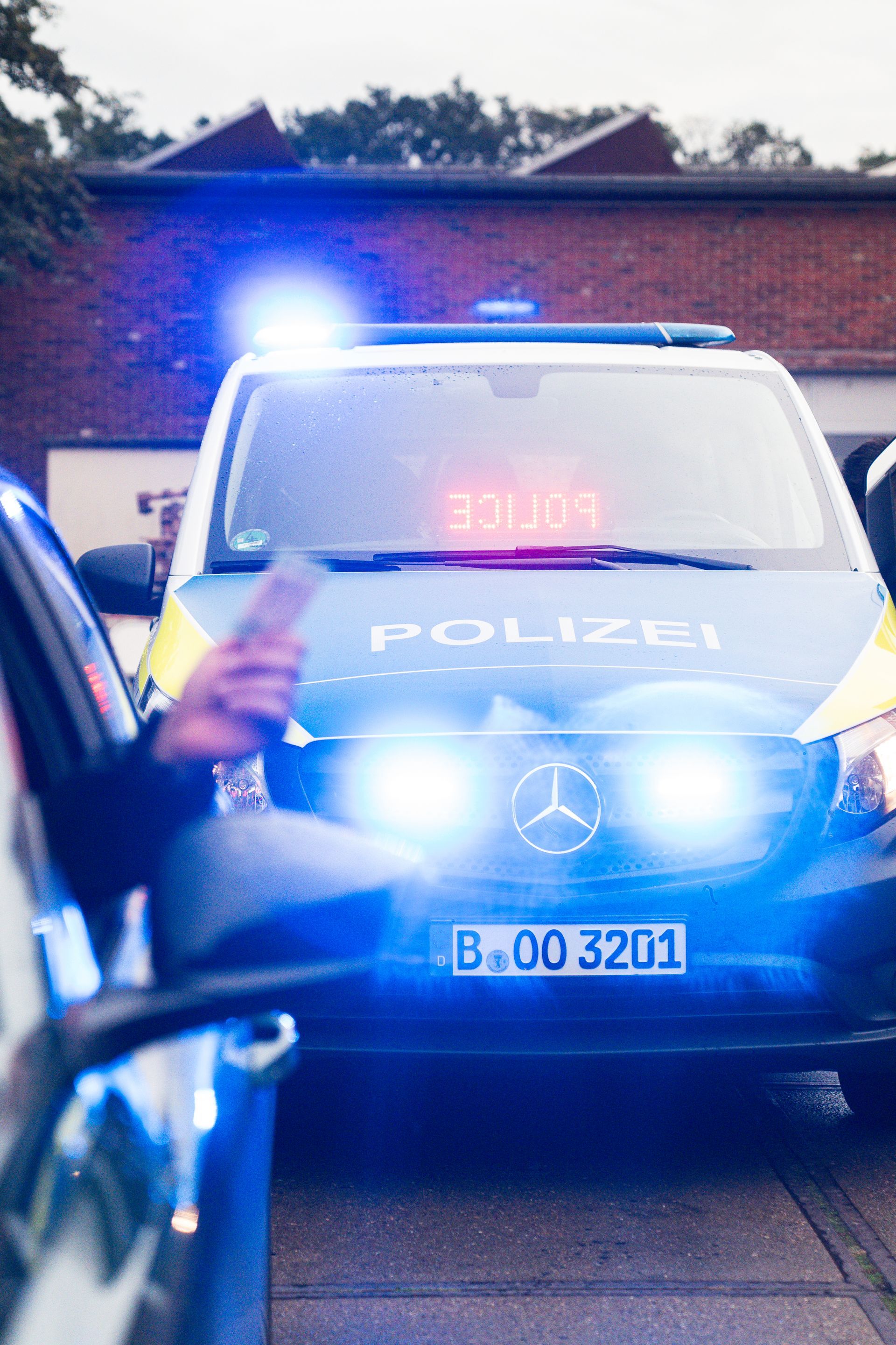 Polizeiwagen mit Blaulicht und Fahrer bei der Dokumentenübergabe in Deutschland.
